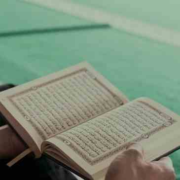 A person is reading the quran on their lap